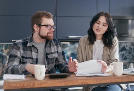 In a business-casual setting, a man explains something to a woman who appears to be his coworker. This photo is used to represent 